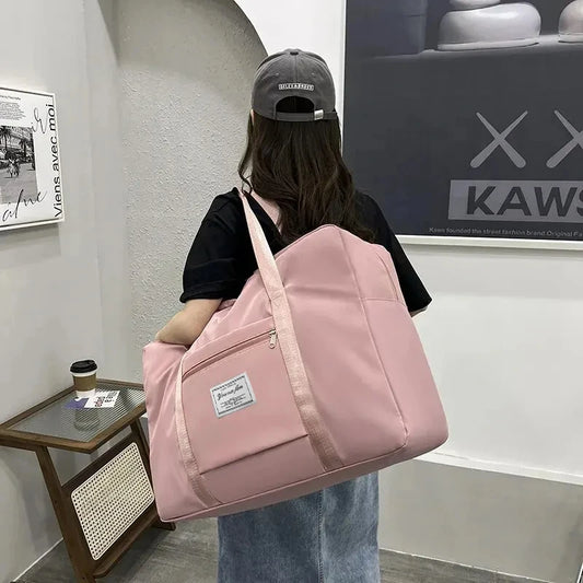 Foldable travel duffel bag in pink worn over the shoulder, lightweight weekend and camp bag